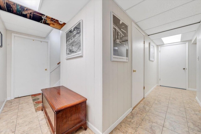 corridor with light tile patterned flooring and baseboards