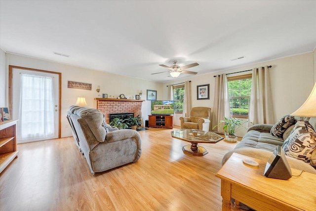 living room featuring light wood-style floors, a ceiling fan, and a fireplace