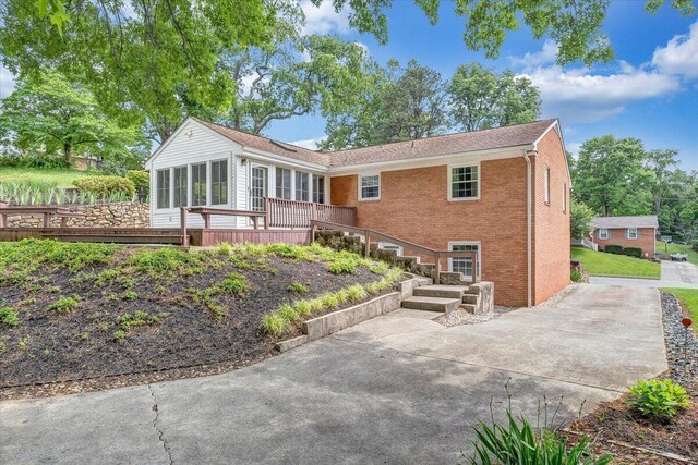 back of house with a sunroom, brick siding, and a deck
