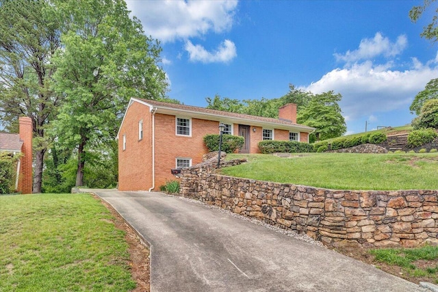 ranch-style house featuring driveway, a chimney, a front yard, and brick siding