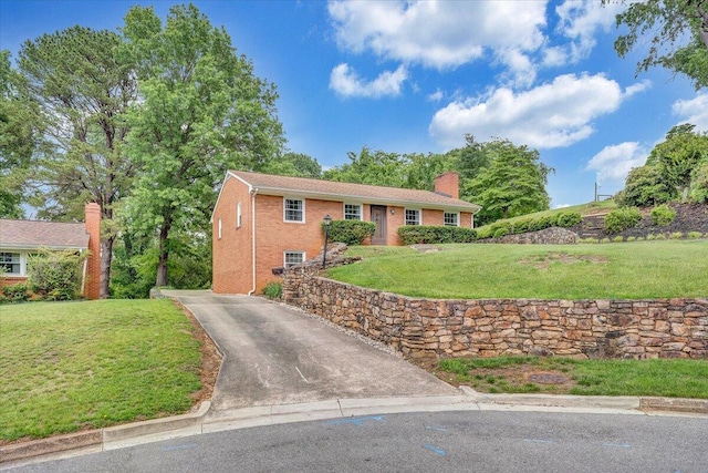 single story home with asphalt driveway, a chimney, a front lawn, and brick siding