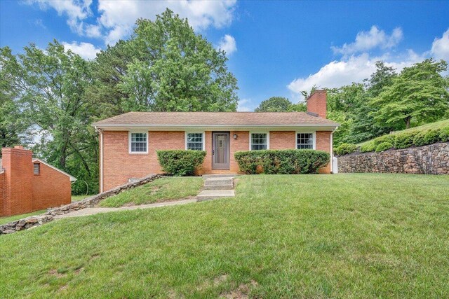 ranch-style home featuring brick siding, a front yard, and a chimney