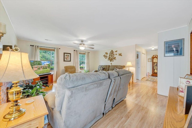 living area with light wood-style floors, a ceiling fan, and ornamental molding