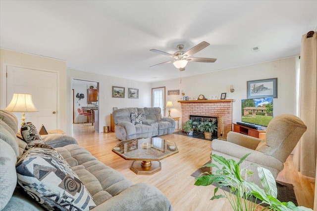living area featuring ceiling fan, wood finished floors, and a fireplace