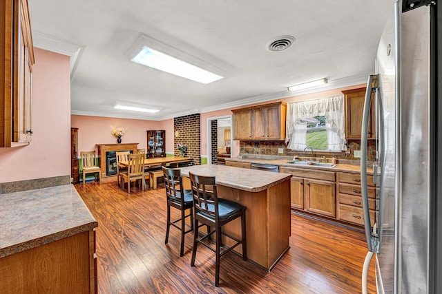 3643 Larson Ln, Roanoke, VA 24018 - kitchen with stainless steel appliances, a sink, ornamental molding, a breakfast bar area, and brown cabinets