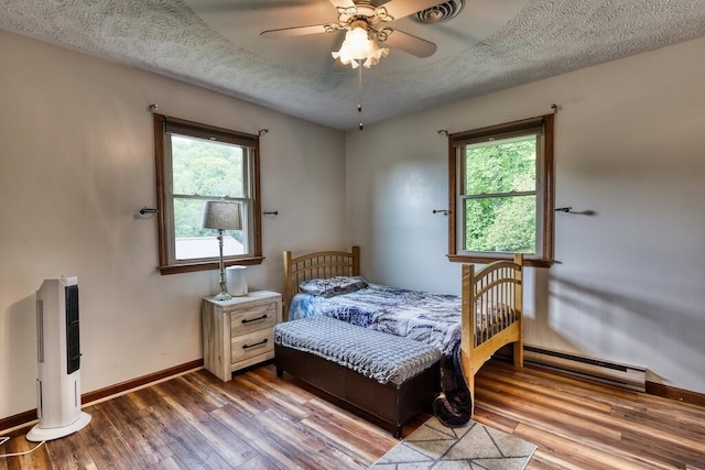 1530 Ridgeview Rd, Floyd, VA 24091 - bedroom featuring a baseboard heating unit, multiple windows, wood finished floors, and a textured ceiling