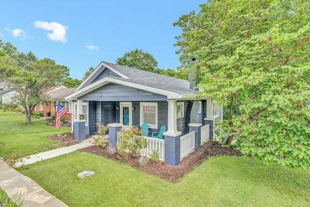 view of front of property featuring a porch, a front lawn, a chimney, and a shingled roof