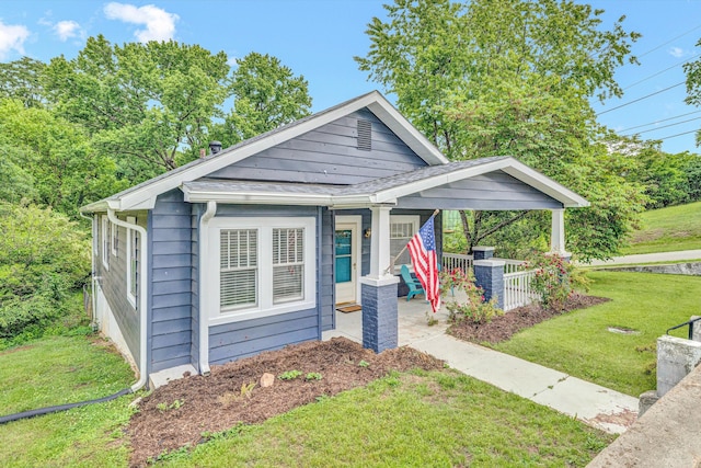 view of front of property featuring a front lawn, covered porch, and cooling unit