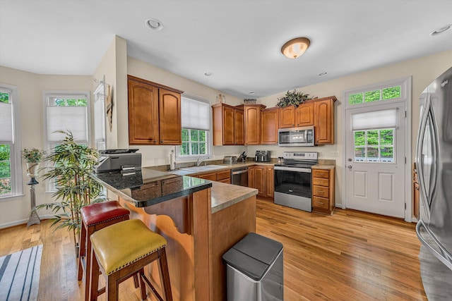1309 W Pine Ridge Rd, Huddleston, VA 24104 - kitchen with appliances with stainless steel finishes, a peninsula, a breakfast bar, light wood-style floors, and a sink