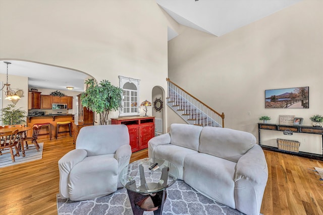 1309 W Pine Ridge Rd, Huddleston, VA 24104 - living area with arched walkways, light wood-type flooring, stairway, a towering ceiling, and a chandelier