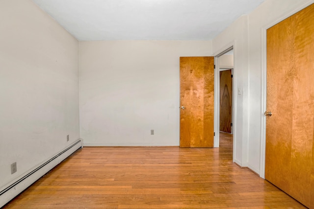 spare room featuring baseboard heating and wood finished floors