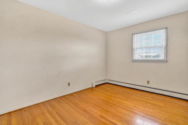spare room with light wood-type flooring, a baseboard radiator, and baseboards
