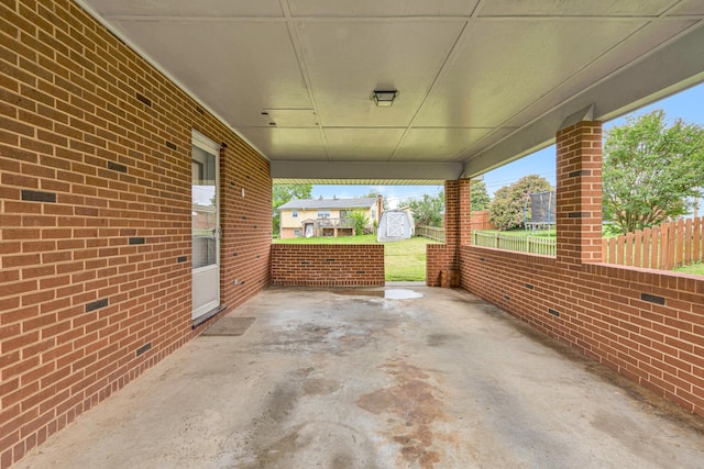 view of patio / terrace featuring a shed, fence, an outdoor structure, and a carport