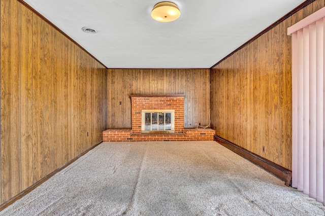 unfurnished living room featuring carpet, a brick fireplace, and wood walls