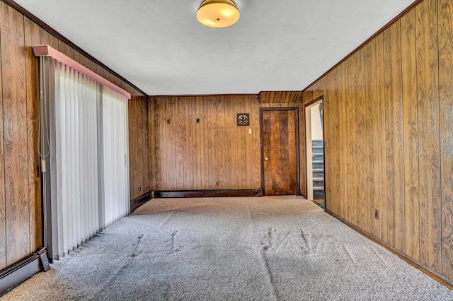 carpeted spare room with wooden walls, a baseboard radiator, ornamental molding, and baseboards