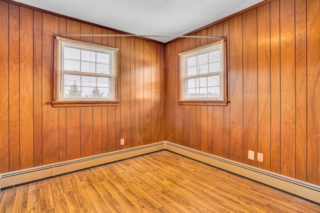 unfurnished room with wood finished floors, wooden walls, crown molding, and a baseboard radiator