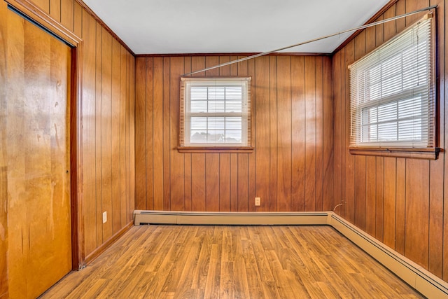 spare room featuring a baseboard radiator, wood finished floors, and wooden walls