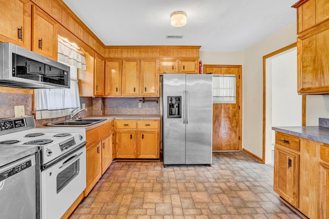 kitchen featuring stainless steel appliances, a sink, baseboards, tasteful backsplash, and brick patterned flooring