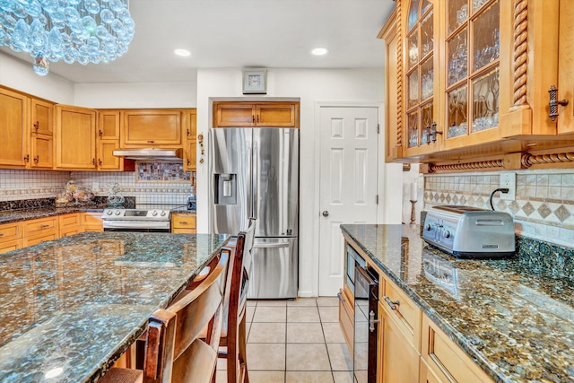 4434 Rosecrest Rd, Roanoke, VA 24018 - kitchen featuring appliances with stainless steel finishes, under cabinet range hood, decorative backsplash, dark stone countertops, and light tile patterned flooring