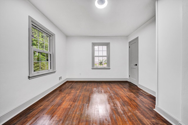 spare room featuring plenty of natural light, dark wood-style floors, and baseboards