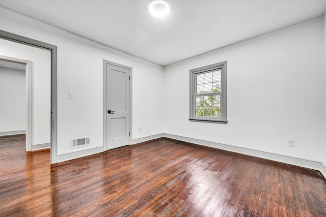 spare room featuring dark wood-style flooring and baseboards