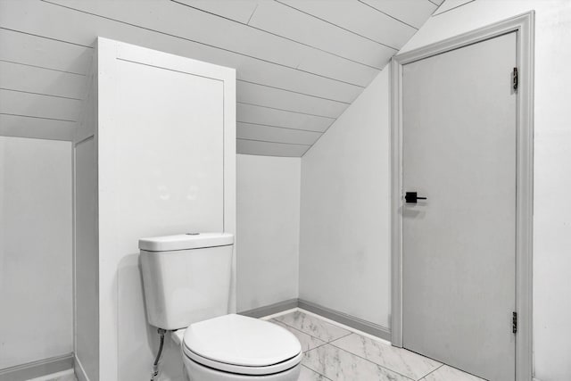 bathroom featuring lofted ceiling, marble look tile flooring, baseboards, and toilet