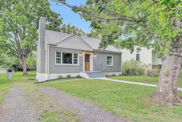 view of front of home with a chimney, a front yard, and brick siding