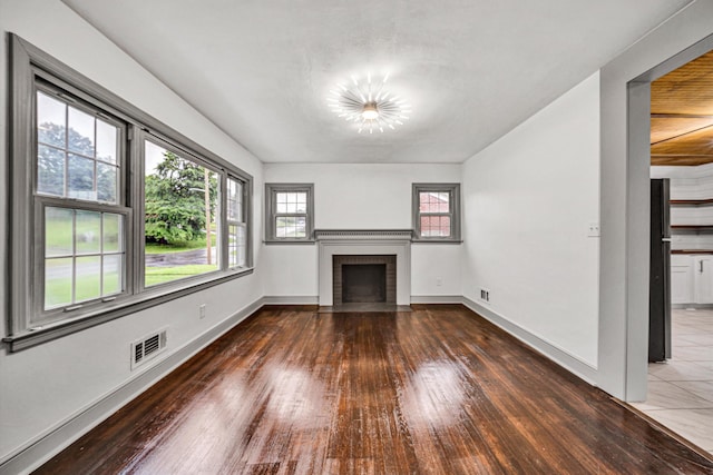 unfurnished living room featuring wood-type flooring, a fireplace, baseboards, and a chandelier