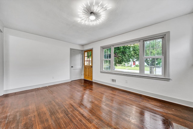 unfurnished room with a chandelier, wood finished floors, and baseboards