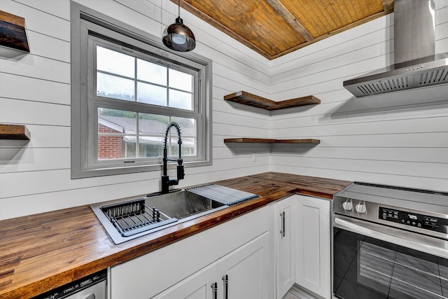 kitchen featuring butcher block countertops, stainless steel appliances, a sink, wall chimney range hood, and wood ceiling