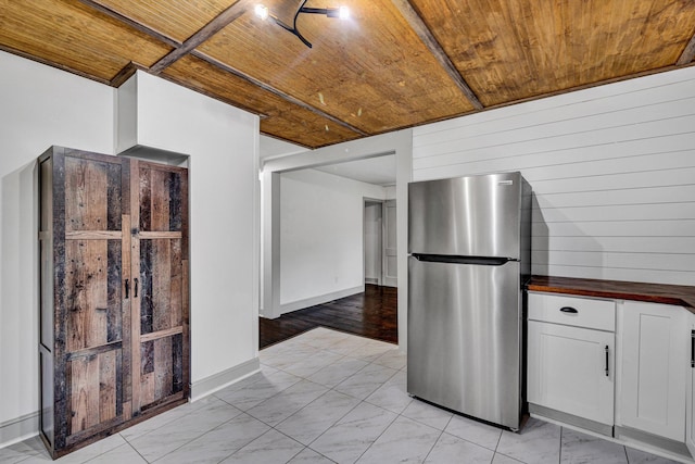 kitchen featuring freestanding refrigerator, wood ceiling, white cabinetry, butcher block countertops, and wood walls