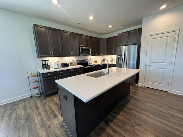 kitchen with stainless steel appliances, a sink, dark wood-style flooring, light countertops, and recessed lighting