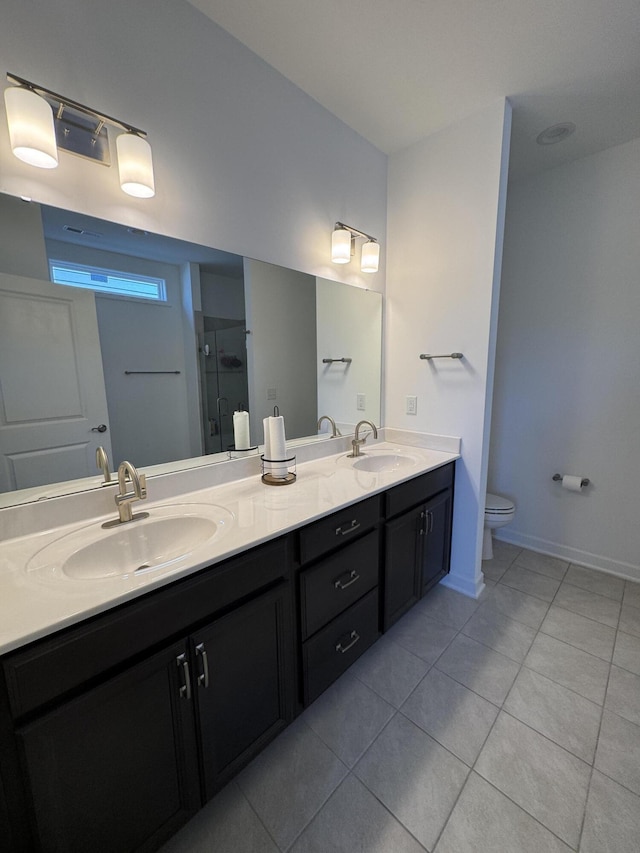 bathroom with tile patterned flooring, toilet, double vanity, a shower with shower door, and baseboards