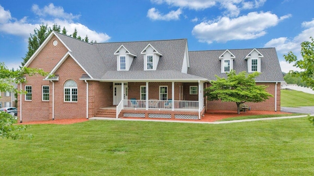 cape cod home with brick siding, covered porch, and a front yard
