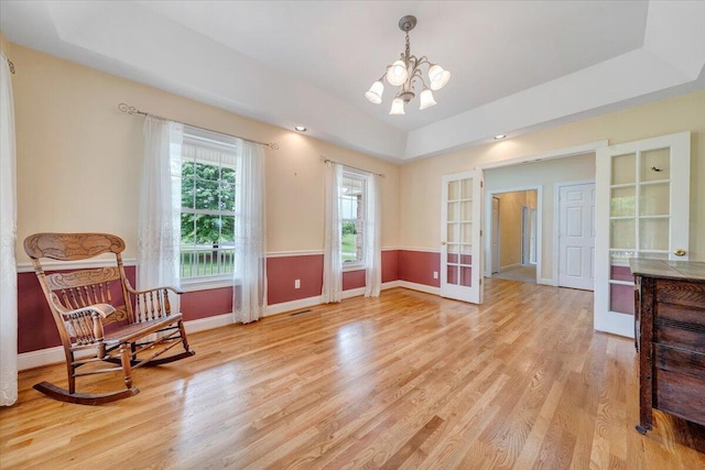 living area featuring french doors, a chandelier, light wood finished floors, and baseboards