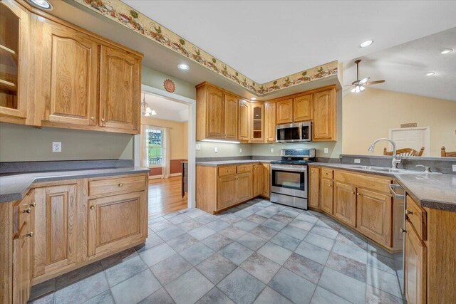 kitchen featuring appliances with stainless steel finishes, a peninsula, ceiling fan, glass insert cabinets, and vaulted ceiling