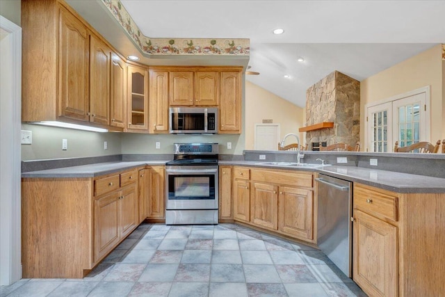 kitchen with stainless steel appliances, a sink, a peninsula, lofted ceiling, and glass insert cabinets
