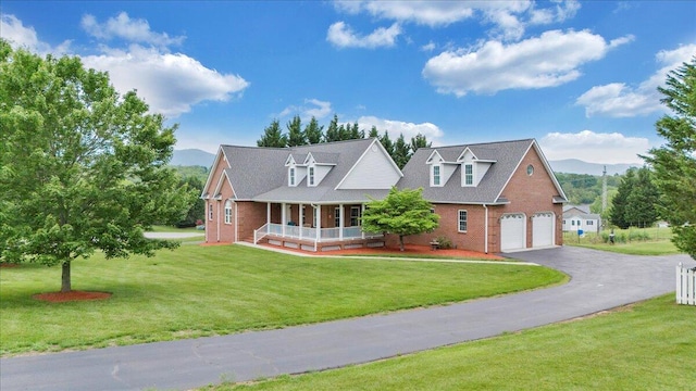 new england style home with a porch, brick siding, a mountain view, and asphalt driveway
