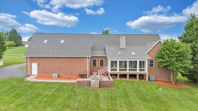 back of house with cooling unit, a sunroom, brick siding, and a yard