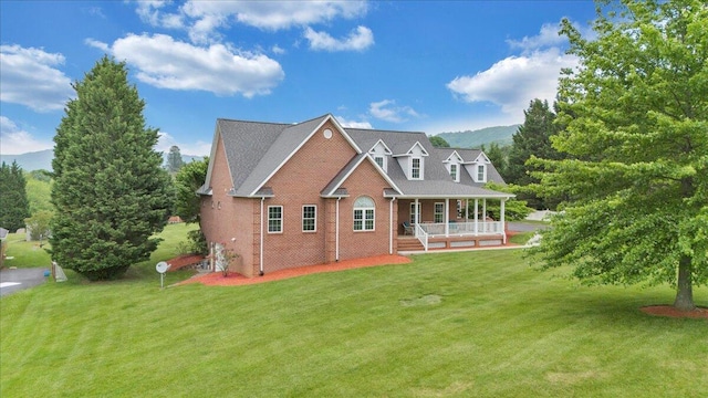 rear view of property featuring covered porch, brick siding, a yard, and a mountain view