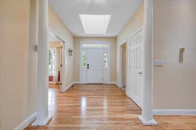entrance foyer featuring light wood-style floors, a skylight, and baseboards