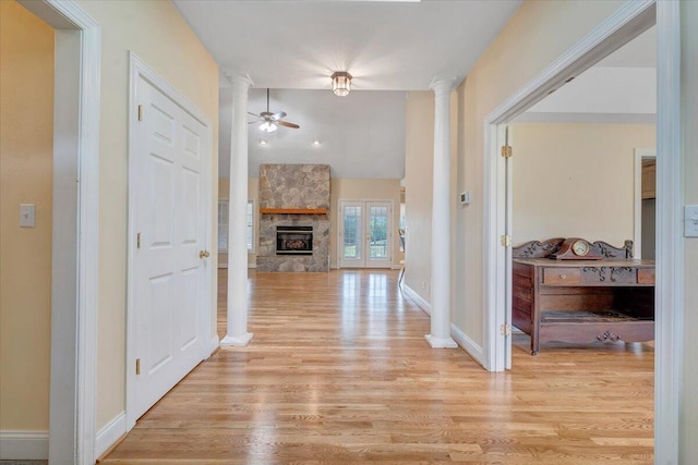 hall with ornate columns, light wood-type flooring, and baseboards