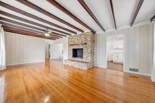 8209 Webster Dr, Roanoke, VA 24019 - unfurnished living room featuring beam ceiling, light wood-type flooring, a brick fireplace, ceiling fan, and baseboards