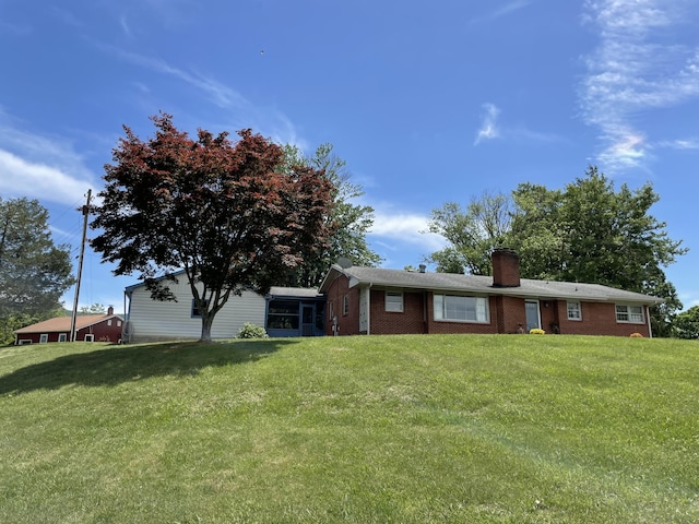 view of front of property with brick siding, a chimney, and a front yard