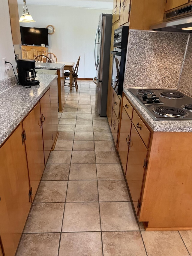kitchen featuring electric cooktop, black oven, under cabinet range hood, freestanding refrigerator, and light tile patterned floors