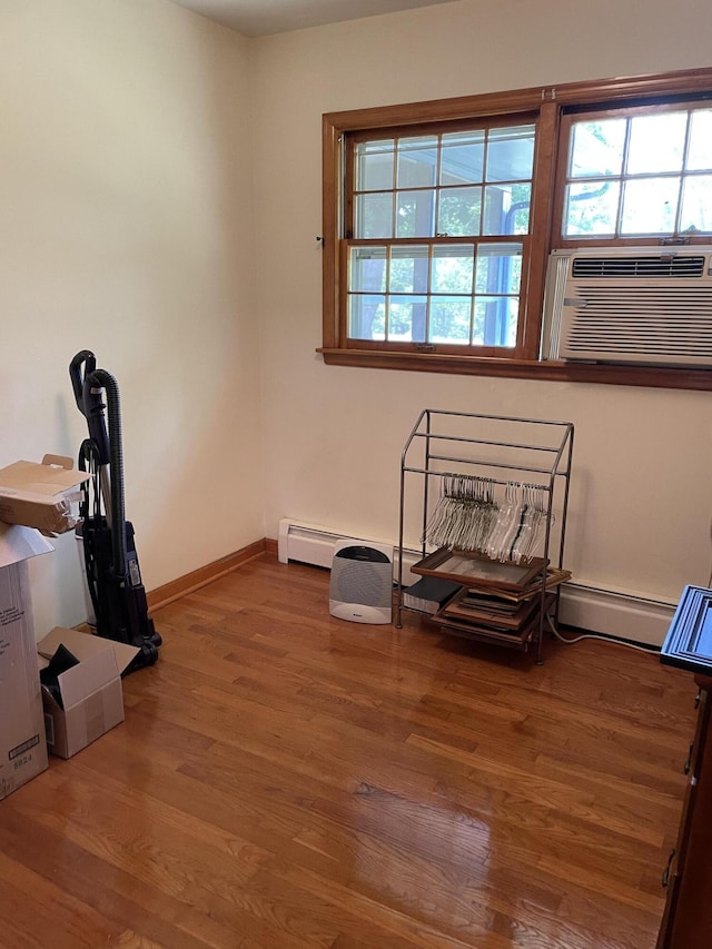 interior space with baseboard heating, wood finished floors, baseboards, and cooling unit