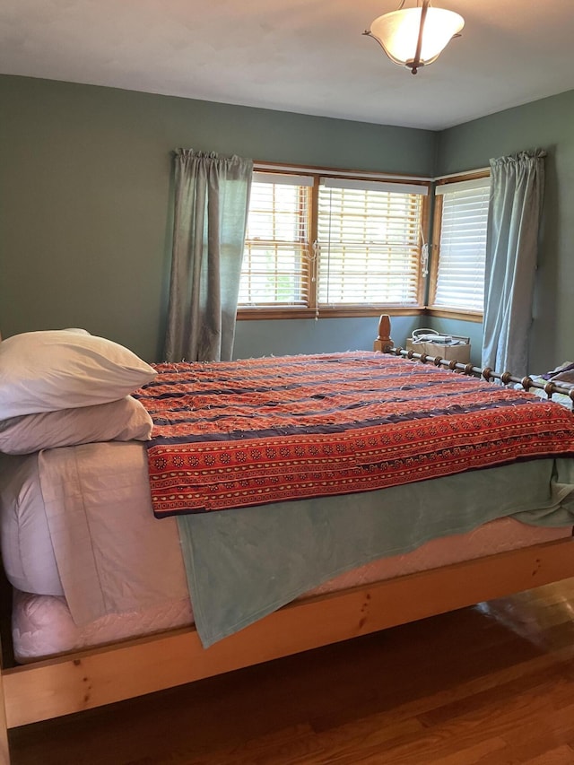 bedroom with multiple windows and wood finished floors