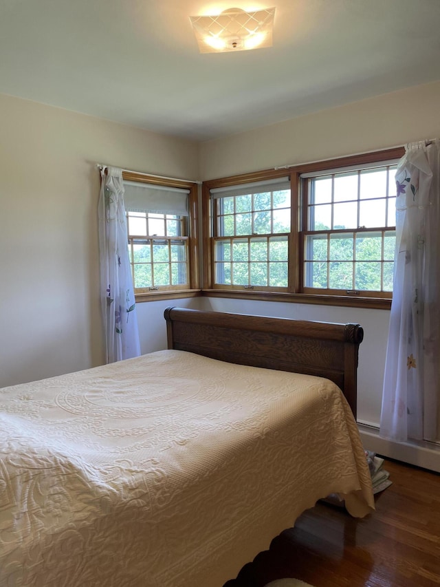 bedroom with wood finished floors and a baseboard heating unit