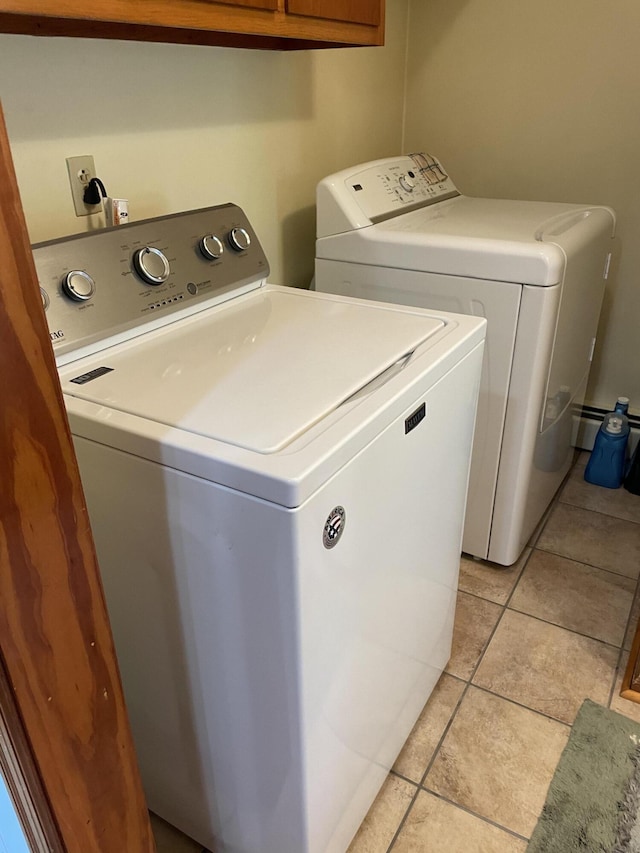 washroom featuring washer and clothes dryer, light tile patterned floors, and cabinet space