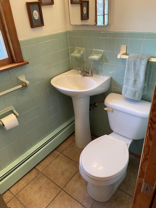 bathroom featuring a baseboard heating unit, toilet, a wainscoted wall, and tile walls